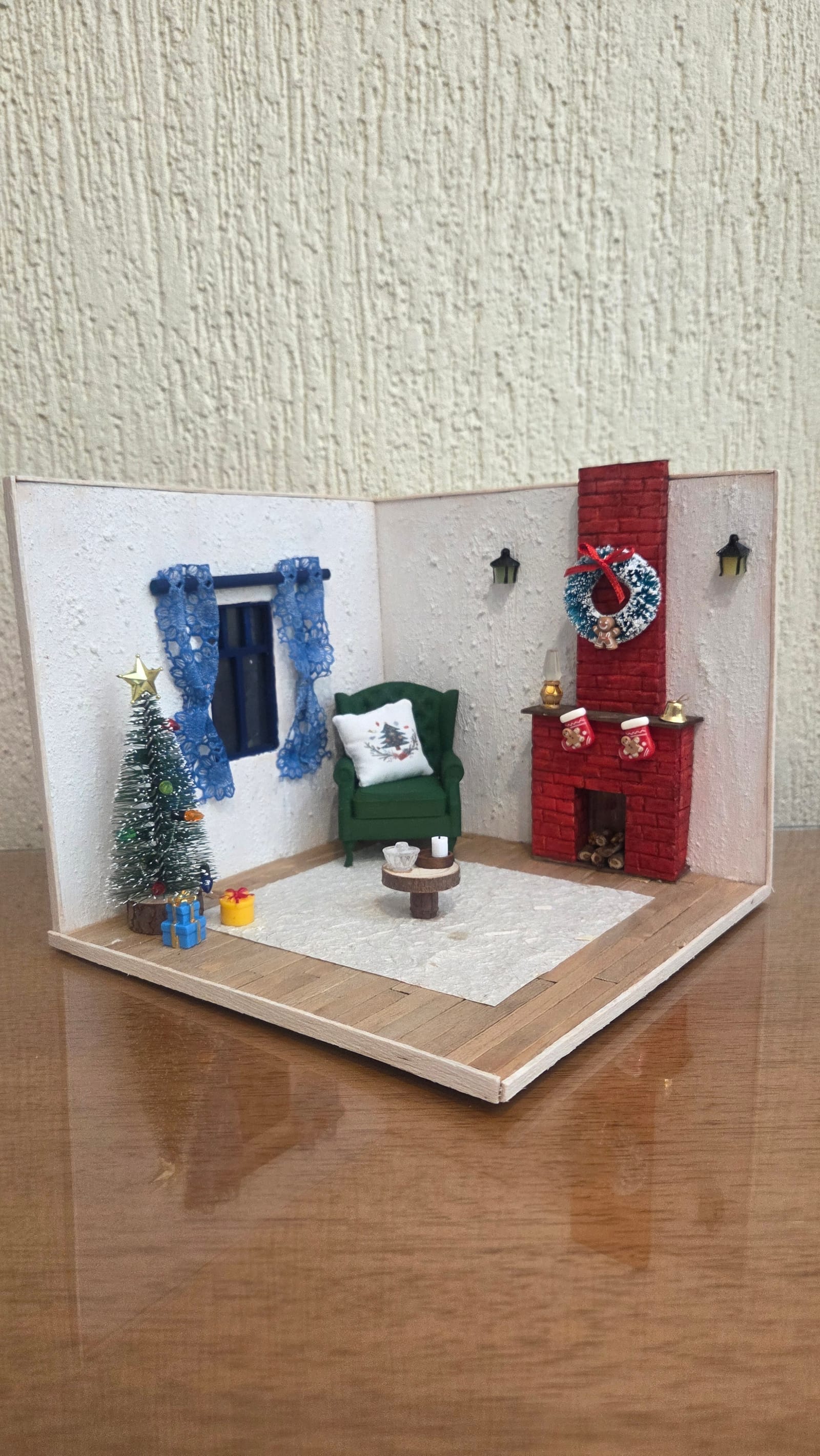 Diorama de canto de sala de Natal com lareira de tijolinhos vermelhos, poltrona verde, cortinas azuis e árvore — vista em ângulo