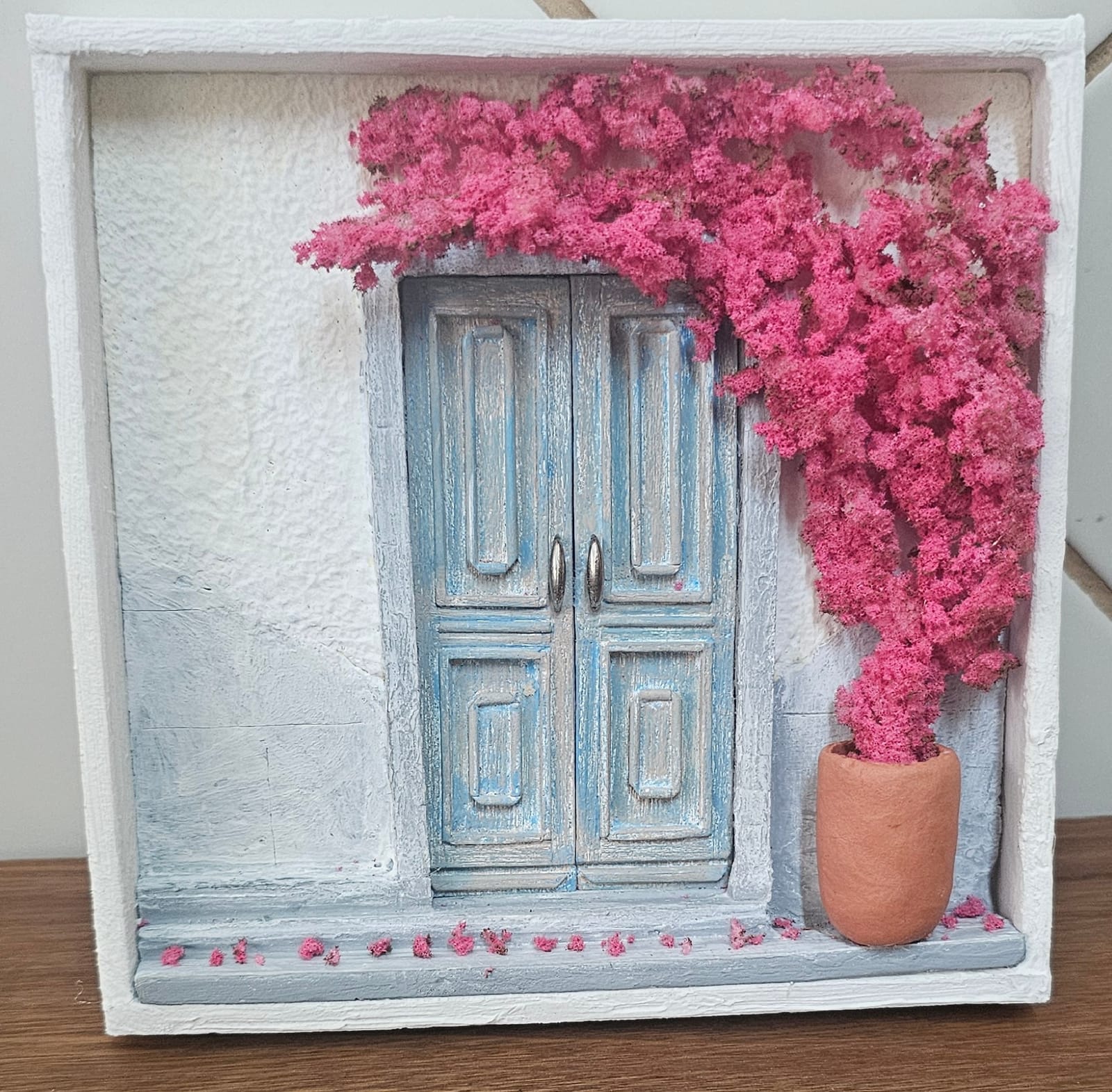 Fachada branca em estilo grego com porta dupla azul envelhecida e primavera rosa florida em vaso de terracota — vista frontal
