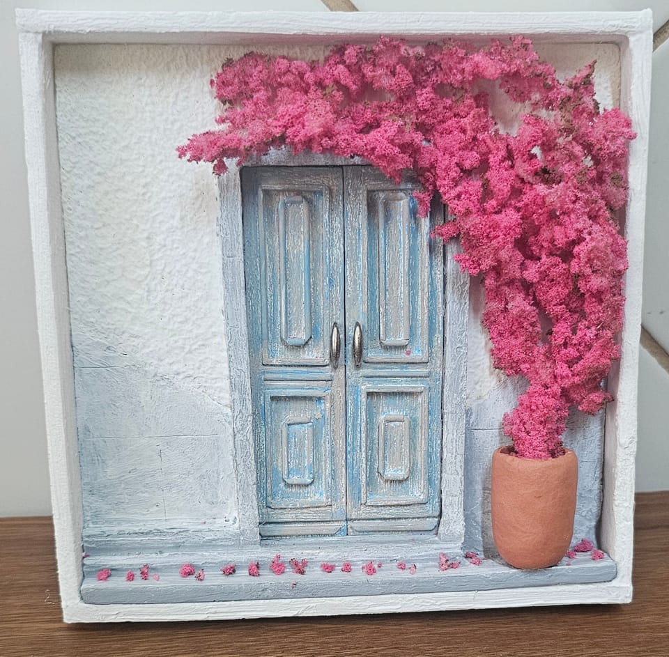 Fachada branca em estilo grego com porta dupla azul envelhecida e primavera rosa florida em vaso de terracota — vista frontal