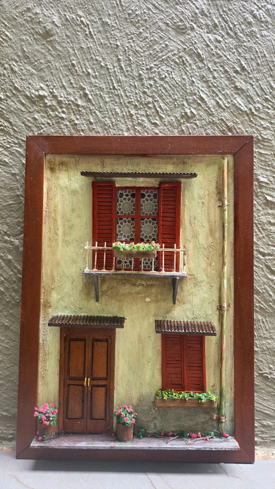 Fachada italiana em moldura com parede verde-claro, venezianas vermelhas, sacada florida e porta de madeira — vista frontal