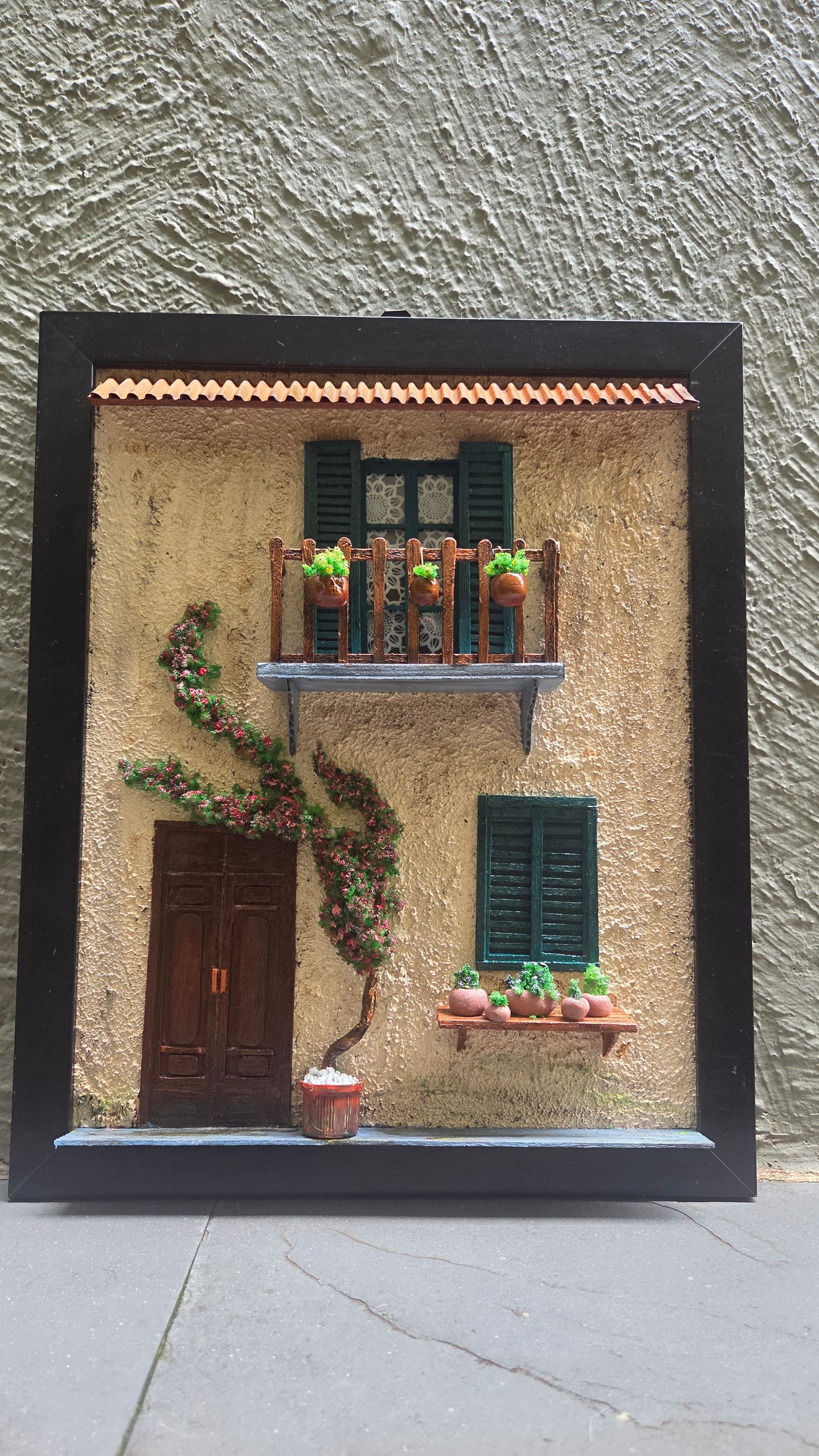 Fachada mediterrânea em moldura com sacada de madeira, vasos, janelas verdes, trepadeira florida e porta de madeira — vista frontal