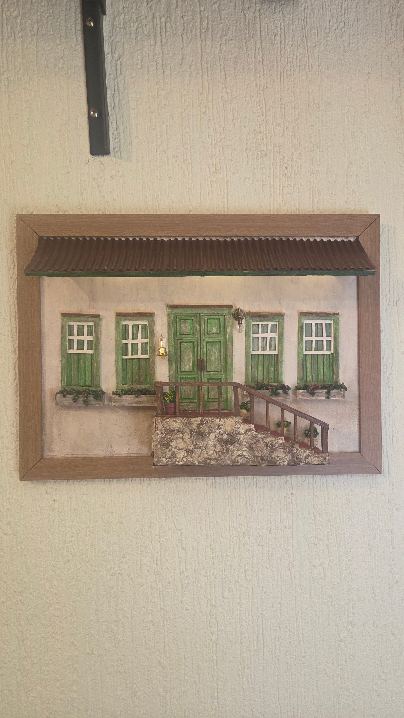 Quadro com fachada colonial de janelas e portas verdes, base de pedra, escadaria vermelha e toldo iluminado — vista frontal