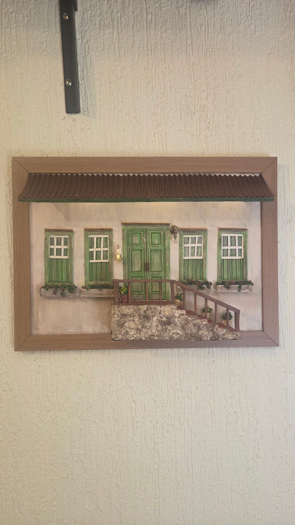 Quadro com fachada colonial de janelas e portas verdes, base de pedra, escadaria vermelha e toldo iluminado — vista frontal